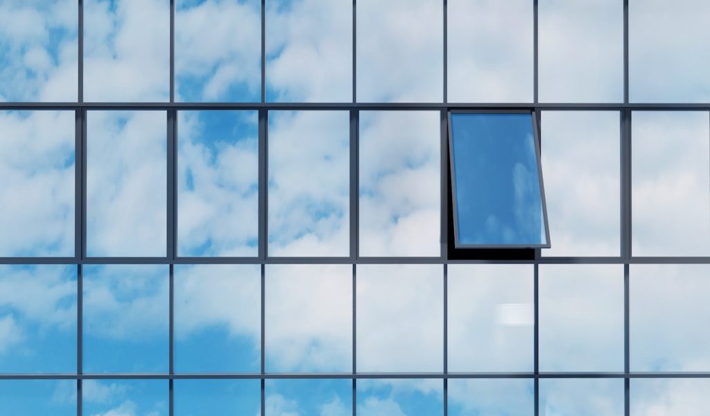 Open glass window with reflection sky on high rise building